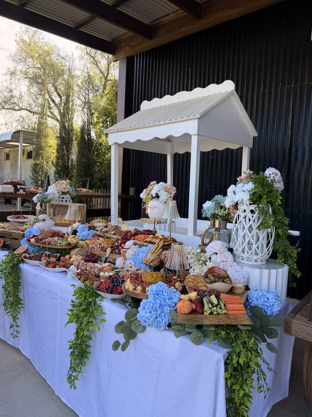 Grazing table under a white gazebo with blue hydrangeas
