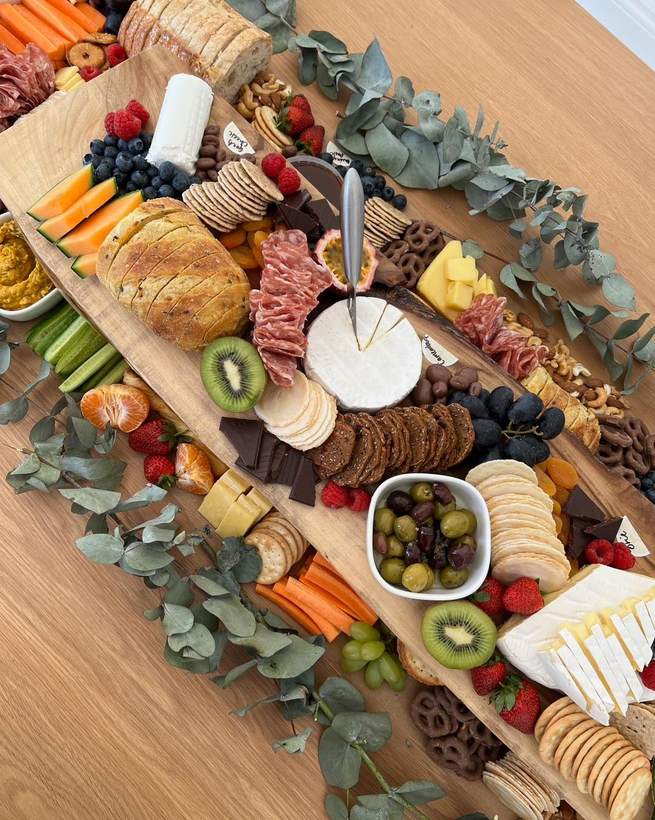 Grazing laid along a timber table with brie and kiwi fruit
